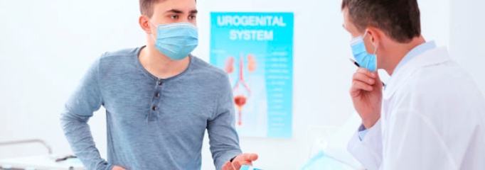 paciente hombre con mascarilla conversa con urólogo en consulta médica