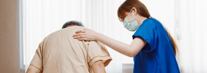 fisioterapeuta con uniforme azul toca la espalda de paciente en hospital para afirmarlo