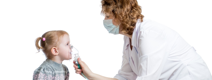 médico mujer con mascarilla coloca mascarilla de oxígeno a niña pequeña sentada en una camilla