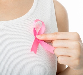 mujer con polera blanca afirma una cinta rosa de cáncer de mama en su pecho