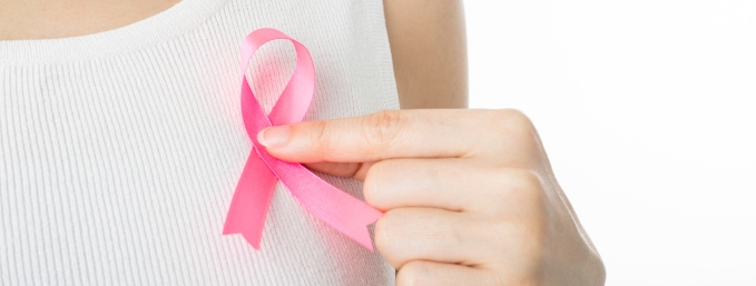 mujer con polera blanca afirma una cinta rosa de cáncer de mama en su pecho
