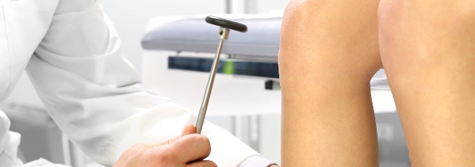 médico toma la pierna de niño y la golpea con instrumento clínico
