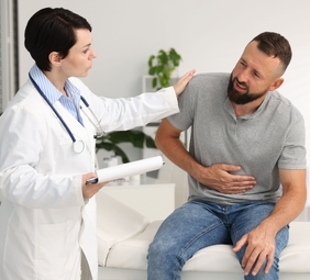 persona con dolor abdominal por úlcera péptica en consulta médica